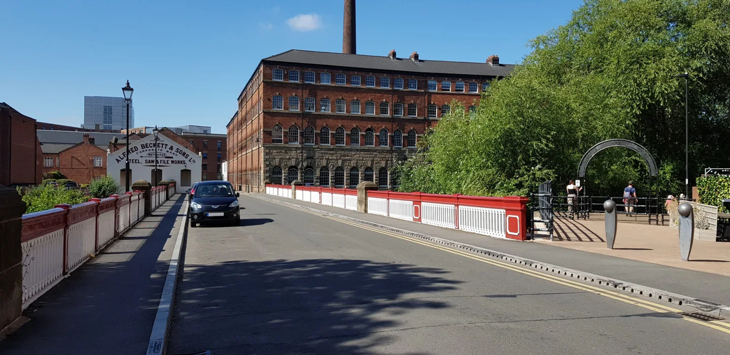 Red and white bridge beside Kelham Island’s historic brick buildings